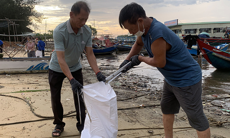 Anh Nguyễn Xuân Thuần (bên trái) tham gia làm vệ sinh bãi biển.