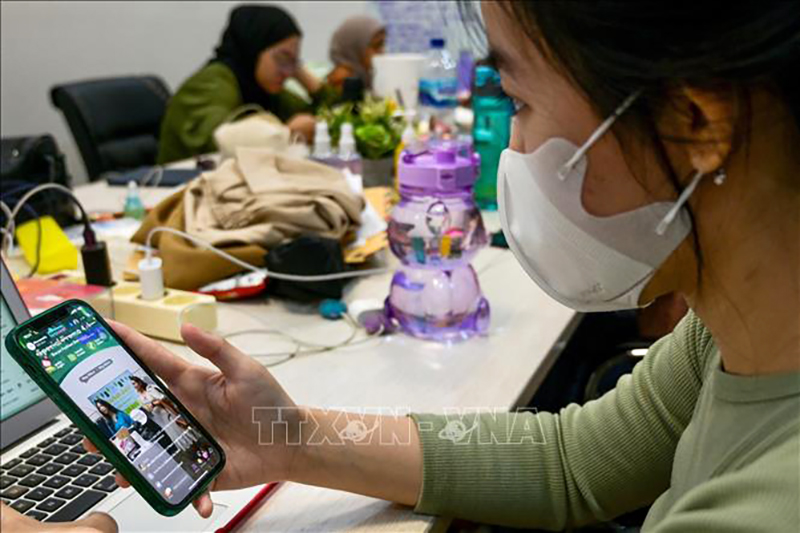 Một phụ nữ xem livestream bán hàng trên ứng dụng TikTok ở Jakarta, Indonesia. Ảnh: AFP/TTXVN