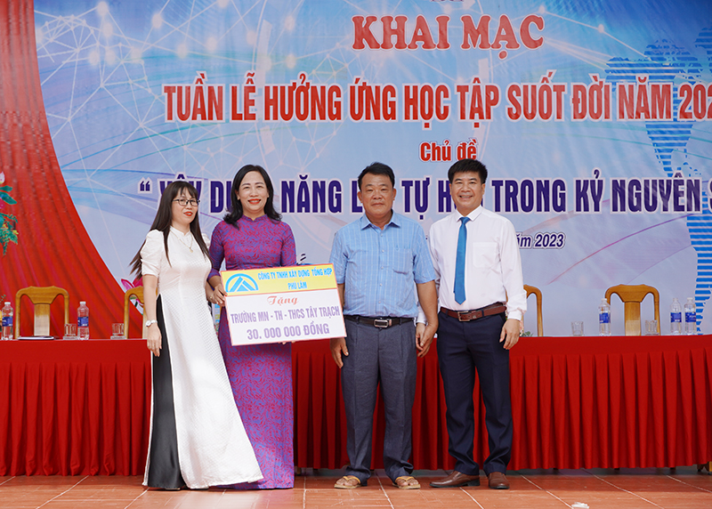 Đại diện lãnh đạo Công ty xây dựng tổng hợp Phú Lâm trao tiền hỗ trợ cho các trường học trên địa bàn xã Tây Trạch.