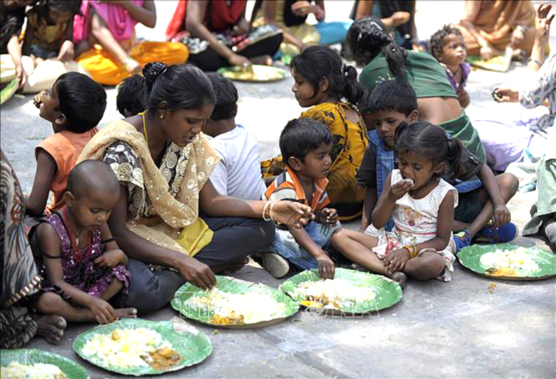  Người vô gia cư nhận thức ăn từ một chương trình cứu trợ dành cho người nghèo ở Hyderabad, Ấn Độ. Ảnh: AFP/TTXVN