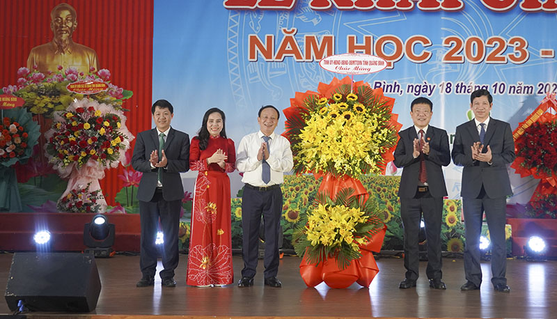 Đồng chí Phó Bí thư Thường trực Tỉnh ủy Trần Hải Châu và đồng chí Phó Chủ tịch UBND tỉnh Hồ An Phong tặng hoa chúc mừng Trường ĐHQB