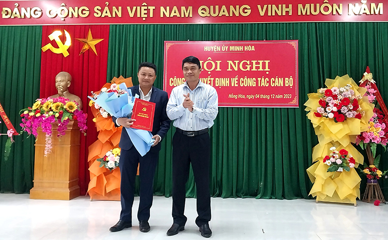 Đồng chí Bí thư Huyện ủy Minh Hóa Bùi Anh Tuấn trao quyết định và tặng hoa chúc mừng đồng chí Đinh Minh Thảo.
