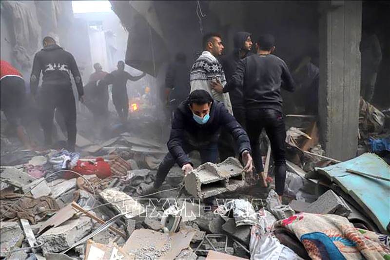 Người dân tìm kiếm nạn nhân trong đổ nát sau cuộc không kích của Israel xuống Dải Gaza, ngày 7/12/2023. Ảnh: THX/TTXVN