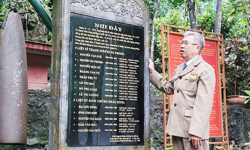 Cựu chiến binh Vũ Hữu Đại bên tấm bia ghi danh 13 liệt sỹ hy sinh ngày 14/11/1972.