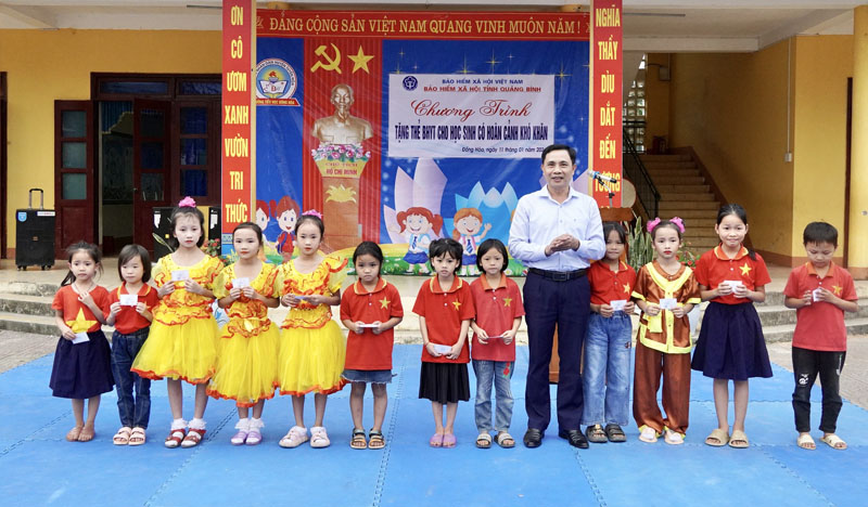 Đại diện lãnh đạo BHXH tỉnh tặng thẻ BHYT cho các học sinh Trường tiểu học Đồng Hóa.