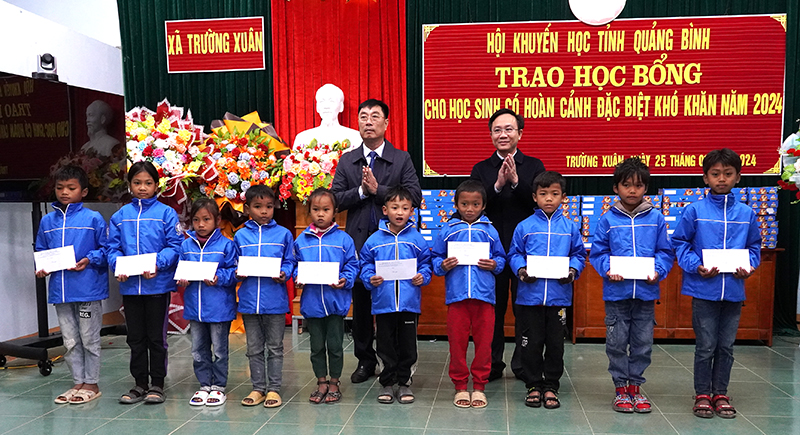 Đồng chí Phó Chủ tịch HĐND tỉnh Hoàng Xuân Tân và đại diện lãnh đạo huyện Quảng Ninh trao học bổng cho các học sinh nghèo vượt khó xã Trường Xuân.