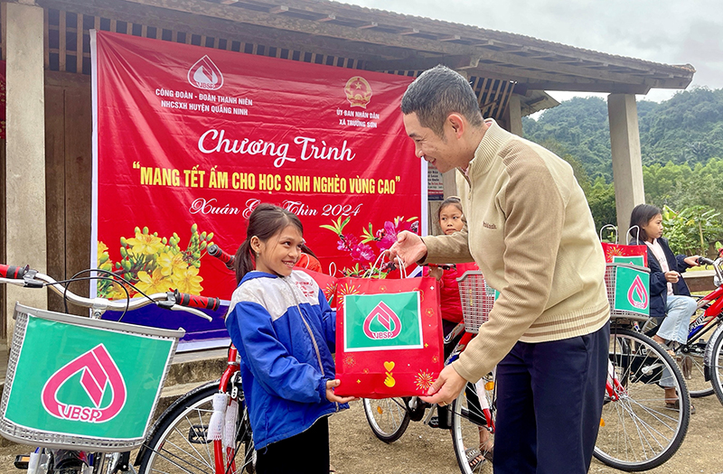 Đại diện lãnh đạo PGD NHCSXH huyện Quảng Ninh tặng quà cho hoc sinh nghèo xã Trường Sơn