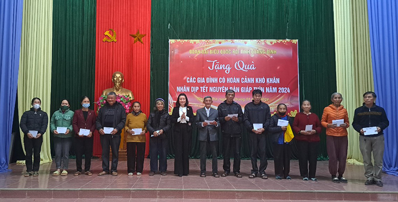 Đồng chí Phó trưởng đoàn chuyên trách Đoàn ĐBQH tỉnh Nguyễn Minh Tâm tặng quà cho các hộ nghèo, cận nghèo ở thị trấn Phong Nha.