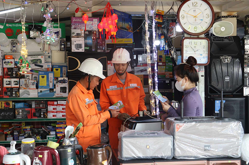 Công nhân PC Quảng Bình đang tuyên truyền sử dụng điện an toàn cho các tiểu thương dịp Tết.
