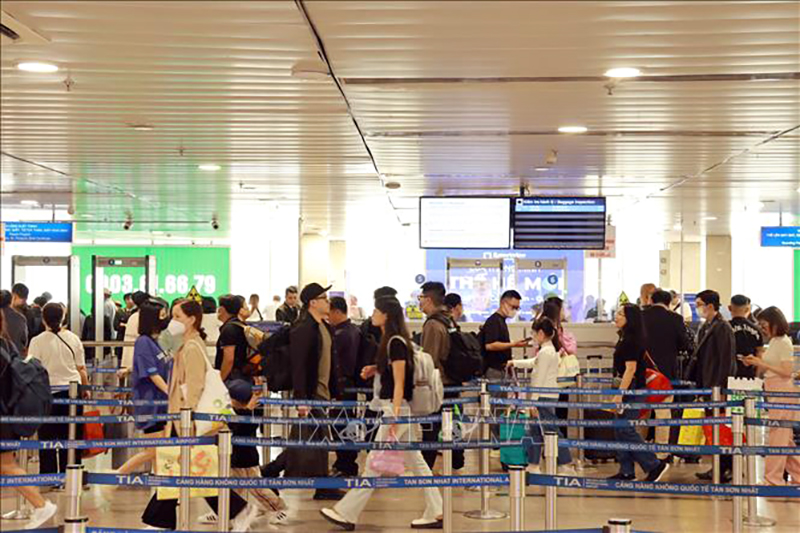 Hành khách xếp hàng làm thủ tục soi chiếu kiểm tra an ninh tại sân bay Tân Sơn Nhất. Ảnh: Quang Châu/TTXVN