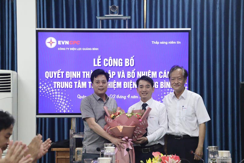 Ông Hoàng Hiếu Trung, Giám đốc PC Quảng Bình tặng hoa chúc mừng Lê Đức Dũng (người đứng giữa) giữ chức Giám đốc Trung tâm Thí nghiệm điện Quảng Bình cho