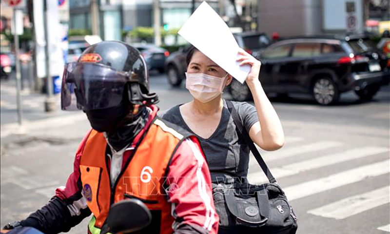 Lái xe công nghệ trang bị trang phục chống nắng dưới tiết trời nóng gay gắt ở Bangkok, Thái Lan. Ảnh: AFP/TTXVN
