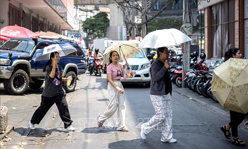 Người dân dùng ô che nắng khi di chuyển trên phố ở Bangkok, Thái Lan. Ảnh tư liệu: AFP/TTXVN
