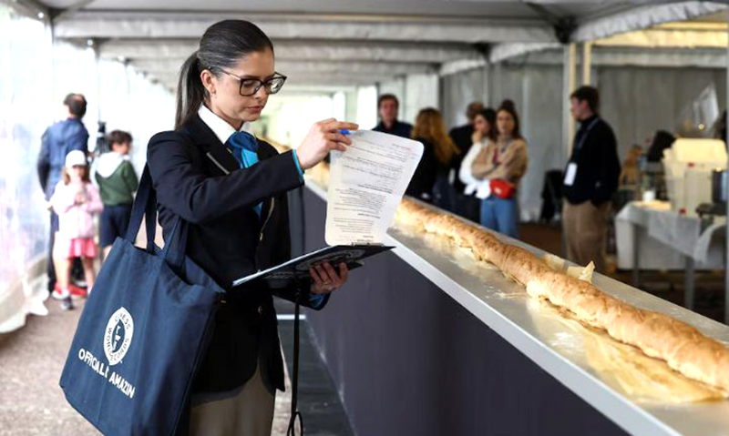 Joanne Brent, giám khảo của Kỷ lục Guinness Thế giới đứng gần chiếc bánh mì baguette trong quá trình kiểm tra nỗ lực đánh bại kỷ lục thế giới về chiếc bánh mì baguette dài nhất trong Triển lãm Bánh mì baguette Suresnes ở Suresnes gần Paris, Pháp, ngày 5/5/2024. Ảnh: Reuters