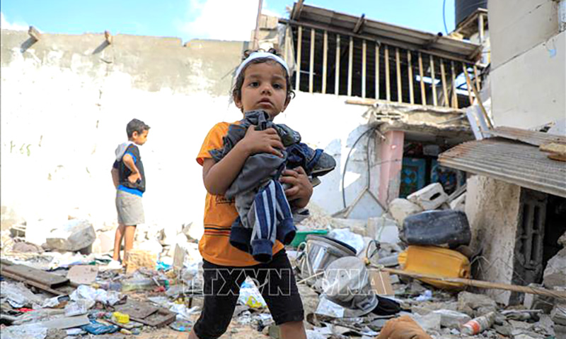  Các em nhỏ thu nhặt đồ đạc sót lại trong đống đổ nát của ngôi nhà bị phá hủy sau cuộc tấn công của Israel vào thành phố Rafah, Dải Gaza ngày 1/5/2024. Ảnh: THX/TTXVN