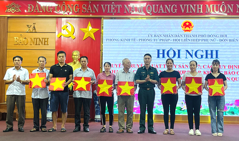 Đại diện lãnh đạo Đồn Biên phòng Nhật Lệ và Ban Tổ chức tặng cờ Tổ quốc cho ngư dân.