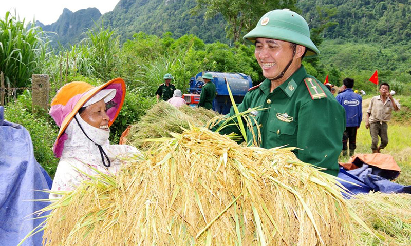 Cán bộ Đồn Biên phòng Cà Xèng giúp dân thu hoạch lúa. Ảnh: Châu Thành