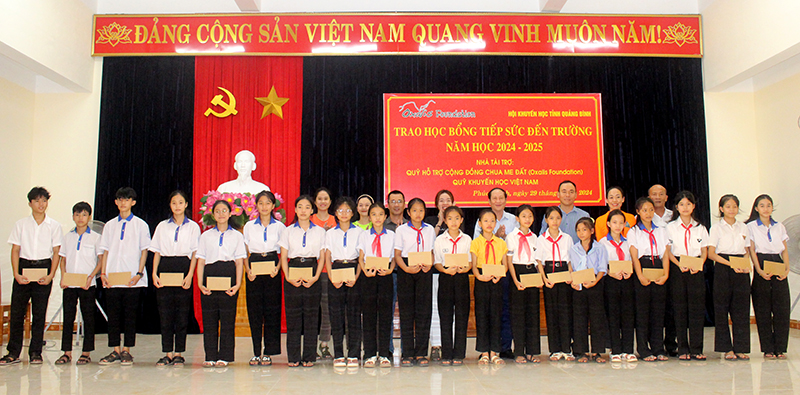 Đại diện nhà tài trợ, Hội Khuyến học và các thầy cô giáo trao học bổng cho các em học sinh trên địa bàn huyện Bố Trạch.