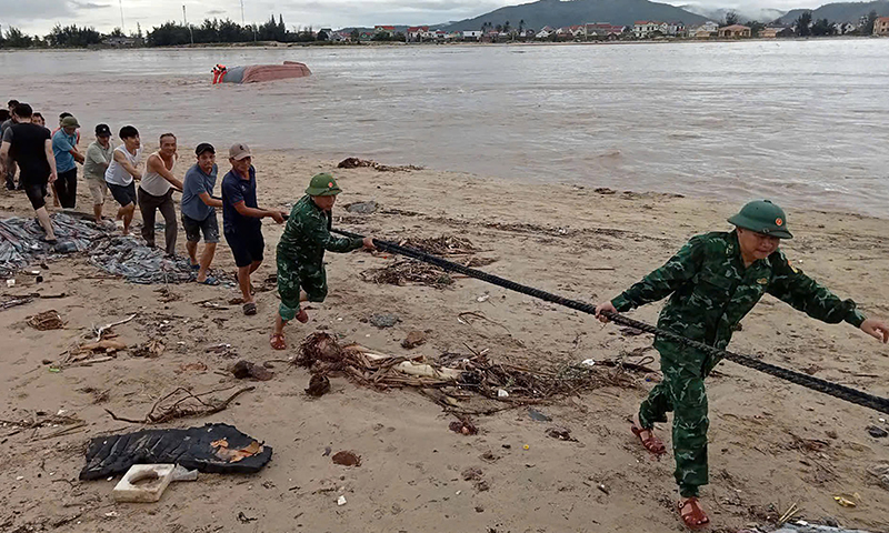 Cán bộ chiến sĩ và nhân dân phối hợp cố định tầu để trục vớt tàu khi lũ rút.