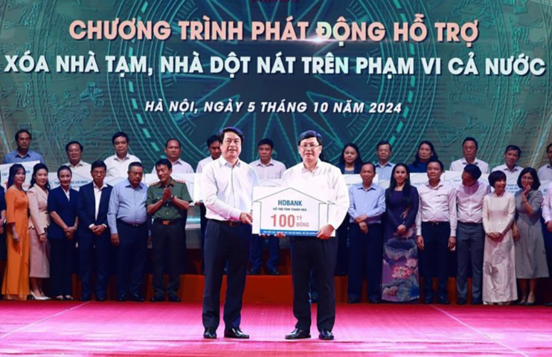 Đại diện Ngân hàng Thương mại cổ phần Phát triển TP. Hồ Chí Minh (HDBank) trao tượng trưng kinh phí hỗ trợ xóa nhà tạm, nhà dột nát cho đại diện địa phương. (Ảnh: Dương Giang/TTXVN)