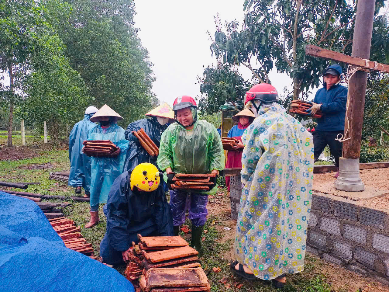 Chị em hội phụ nữ Yên Hóa đội mưa giúp đỡ các gia đình sửa chữa nhà tạm, nhà dột nát.