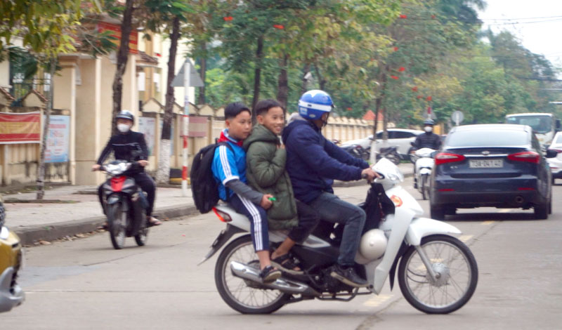 Tình trạng phụ huynh không đội mũ bảo hiểm cho con vẫn còn xảy ra tại các trường học.