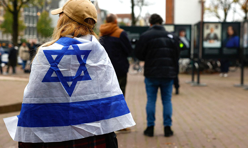 Một người phụ nữ quấn cờ Israel đứng bên ngoài nơi thị trưởng Amsterdam Femke Halsema tham dự cuộc họp báo sau vụ bạo lực nhắm vào người hâm mộ đội bóng đá Israel, tại Amsterdam, Hà Lan, ngày 8/11/2024. Ảnh: Reuters