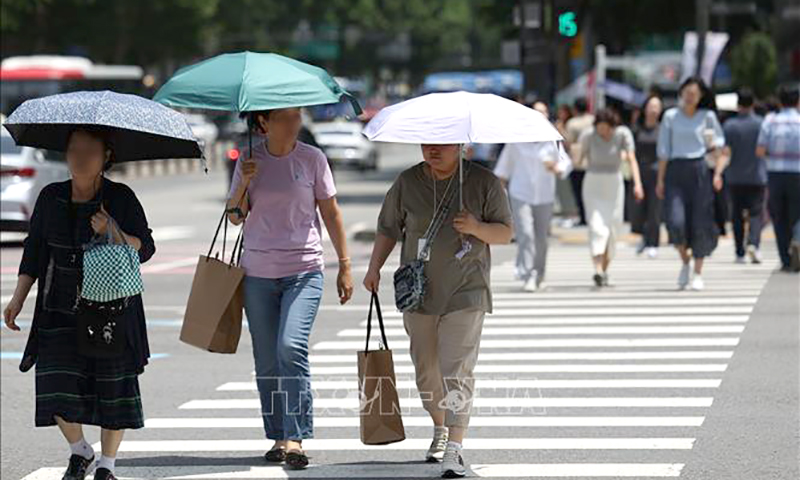 Người dân di chuyển trên đường phố dưới trời nắng nóng tại Seoul, Hàn Quốc, ngày 17/6/2024. Ảnh minh họa: Yonhap/TTXVN