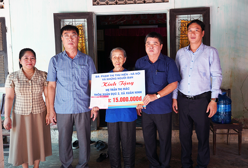 Lãnh đạo UBND huyện Quảng Ninh và các mạnh thường quân trao tặng sổ tiết kiệm cho bà Trần Thị Mác.