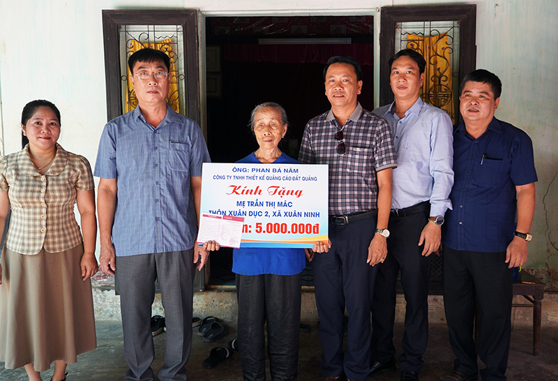 Lãnh đạo UBND huyện Quảng Ninh và các mạnh thường quân trao tặng sổ tiết kiệm cho bà Trần Thị Mác.